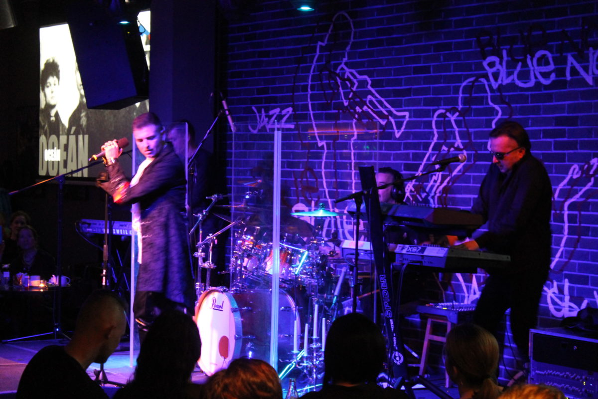 Koncert kapely na pódiu s osvetlením a ozvučením.